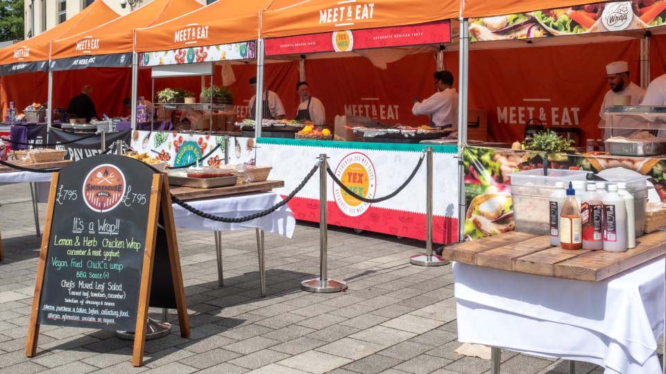 A view of the orange-coloured Meet and Eat tents serving freshly cooked foods in sunny Shirley Pearce Square.