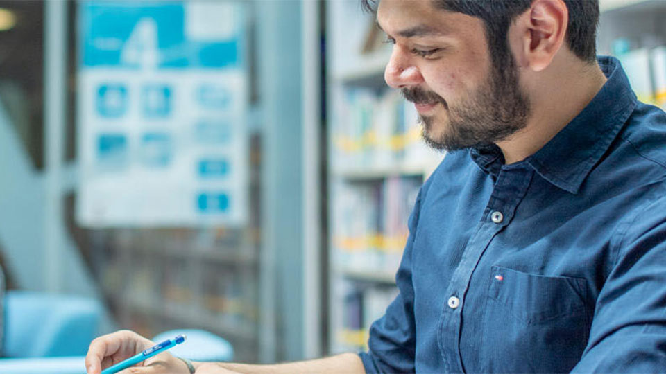 student smiling looking at work on a table