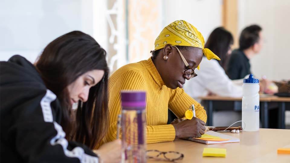 Students sat at a table writing during a doctoral training session.