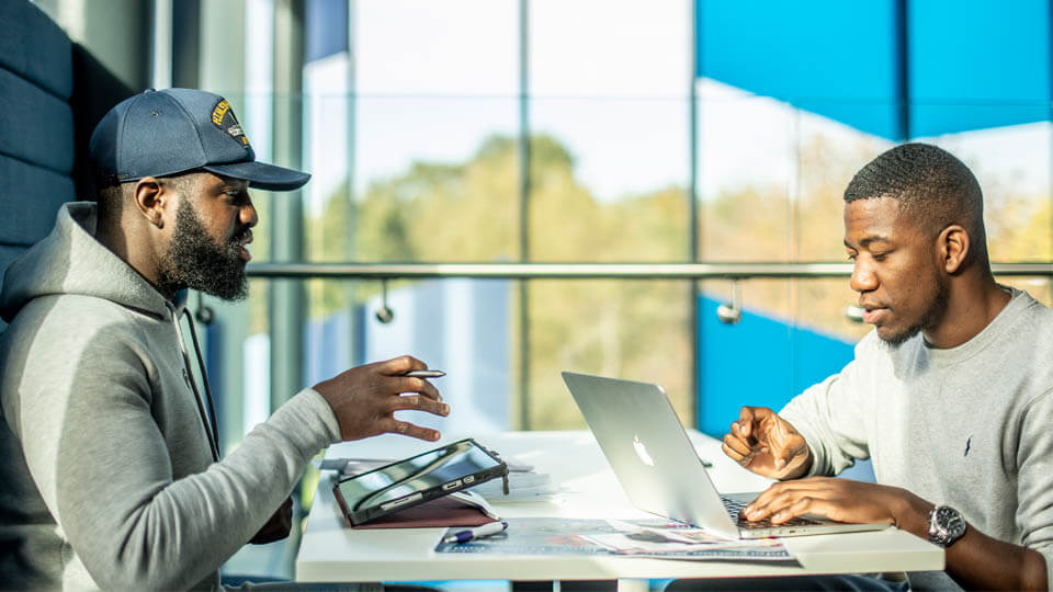 two students talking and using computers