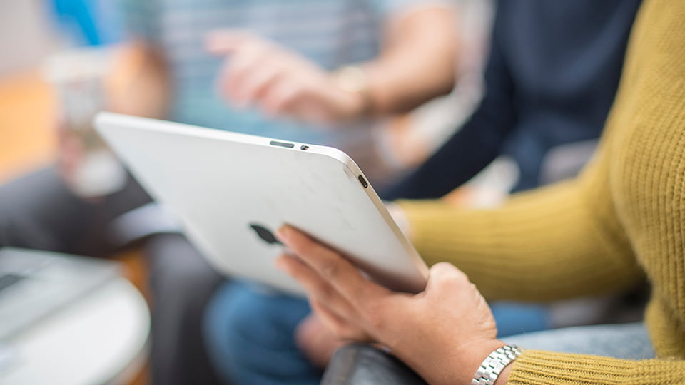 A person holding an iPad and showing what is on screen to the people next to them.