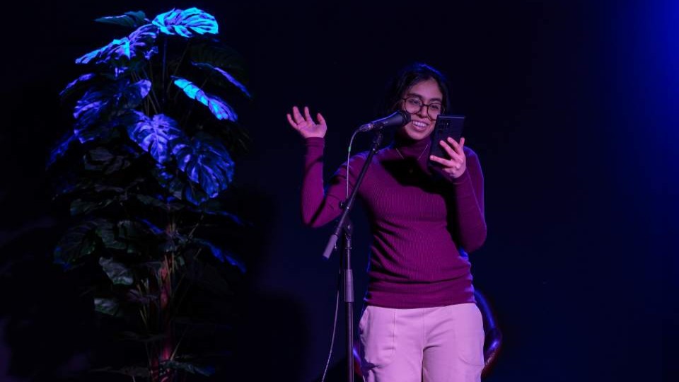 A student on stage reading out their creative writing.