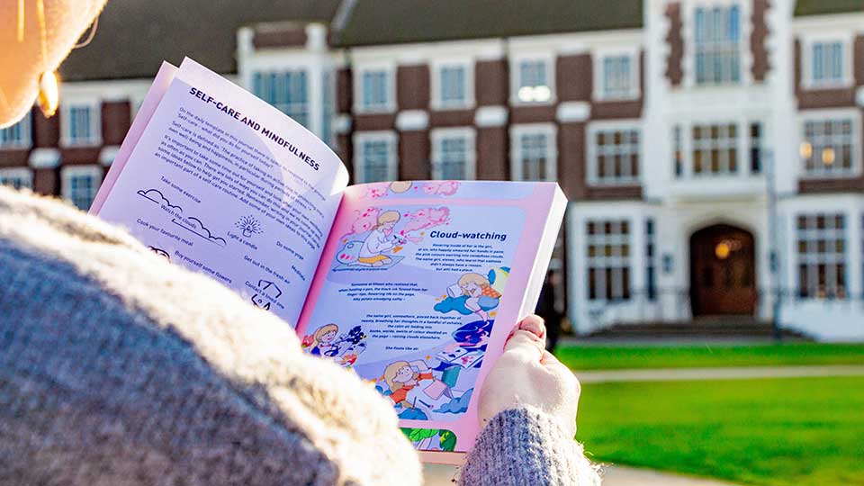 A student sat looking at their notebook outside.