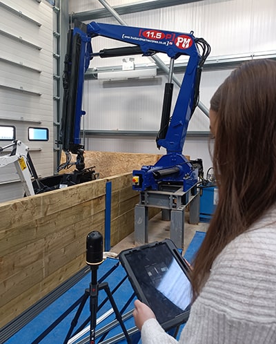 A student holding a tablet and standing next to an imaging laser scanner.