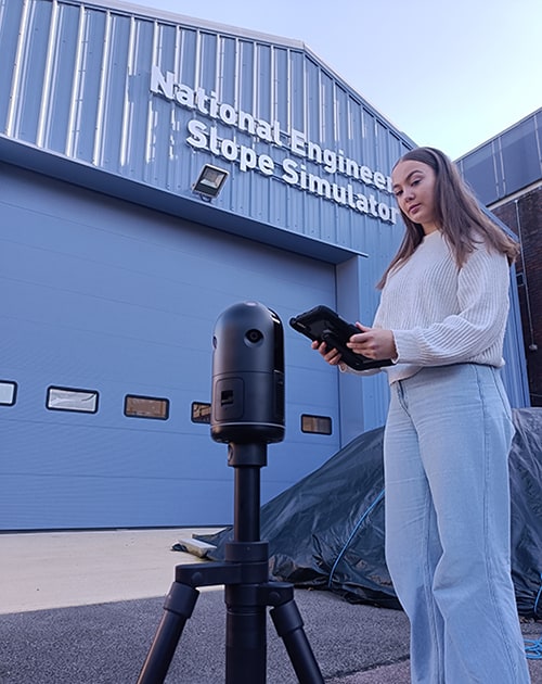 A student using a laser scanner outside of the National Engineering Slope Simulator facility.