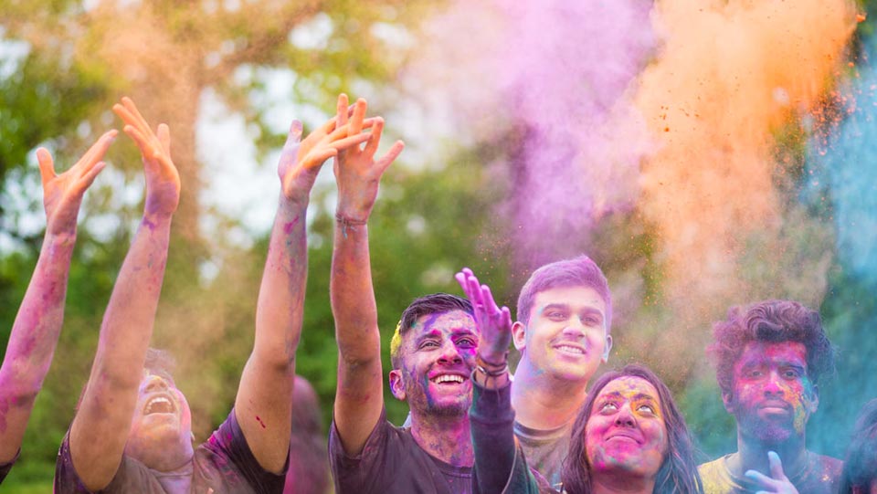 a group of students throwing coloured powder into the air