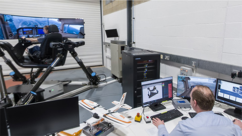 A still from a 360 degree image of a student sitting in a flight simulator while a technician controls it on a computer