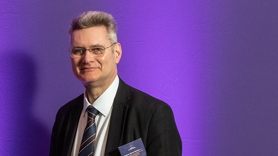 Headshot of Michael, smiling with a purple background.