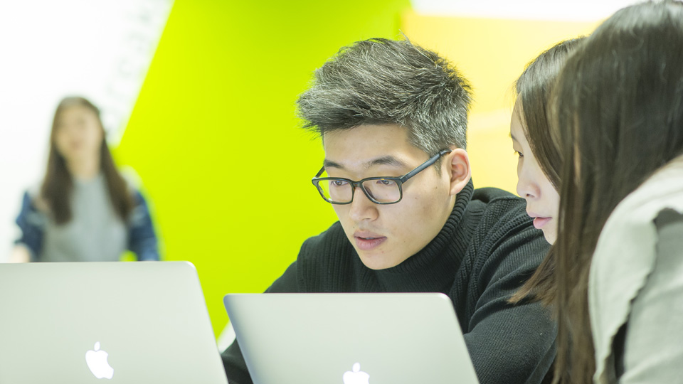 3 students looking at laptops