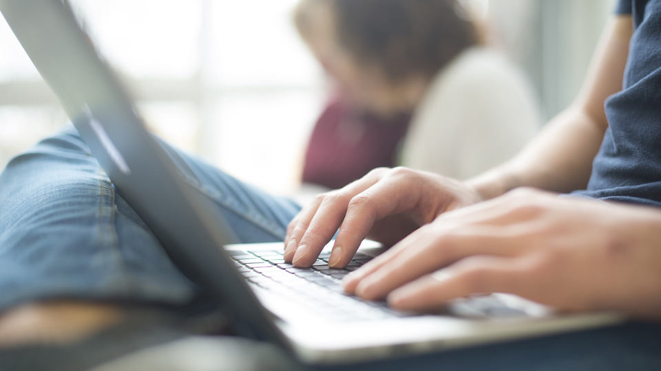 close up of hands typing on laptop keys