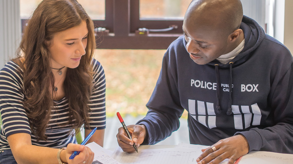 two people sitting at a table with papers in front of them