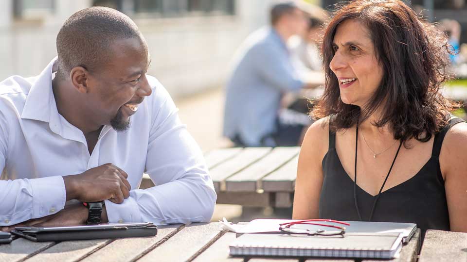 two students having a conversation sitting outside