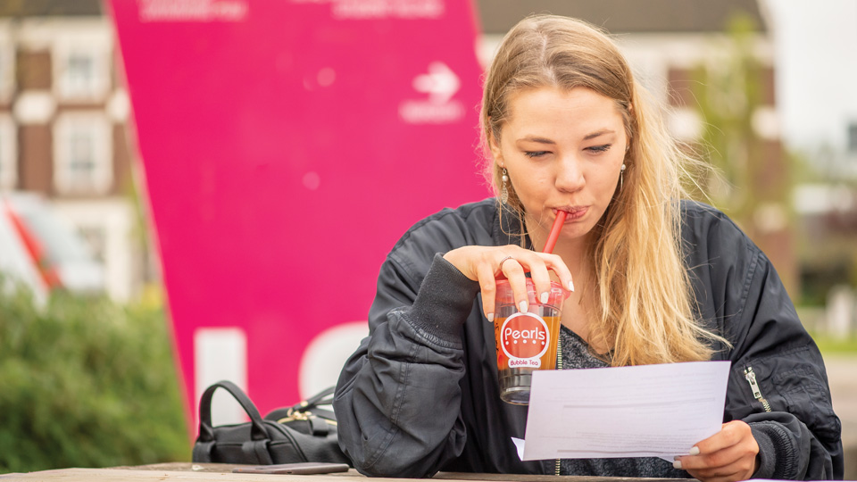 a student sitting outside drinking tea and reading