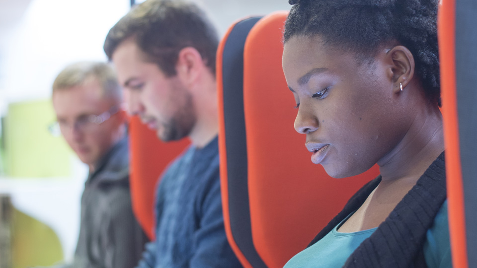 three students sitting in a row looking at computers