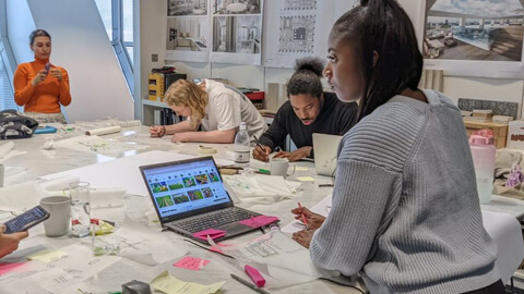 Student standing at a desk looking at architectural plans at a SOM Design workshop on Sustainability and Liveability.