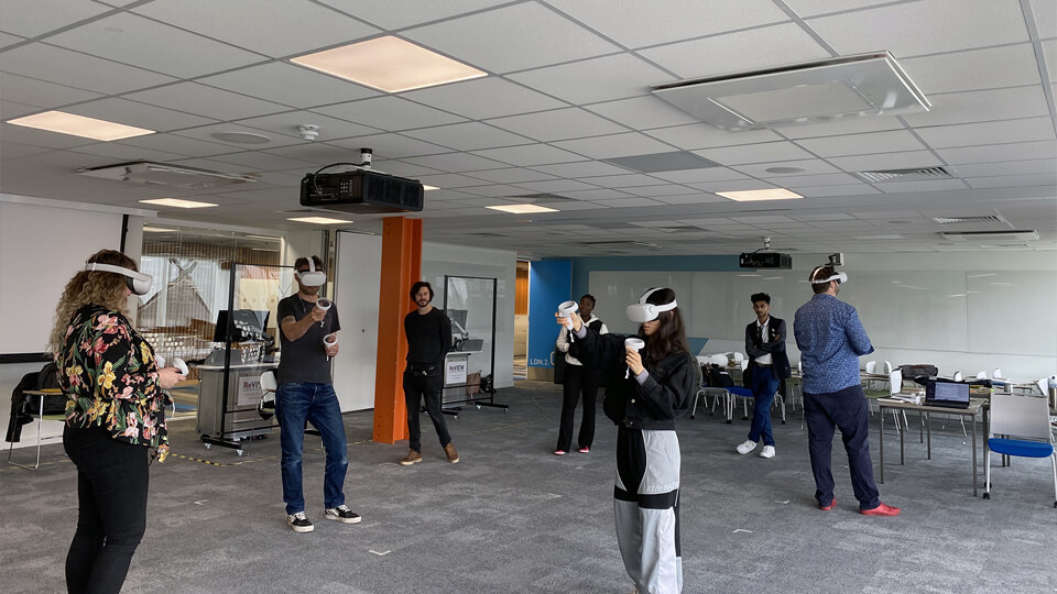 Students and staff in a well-lit office wearing VR headsets in an open office.