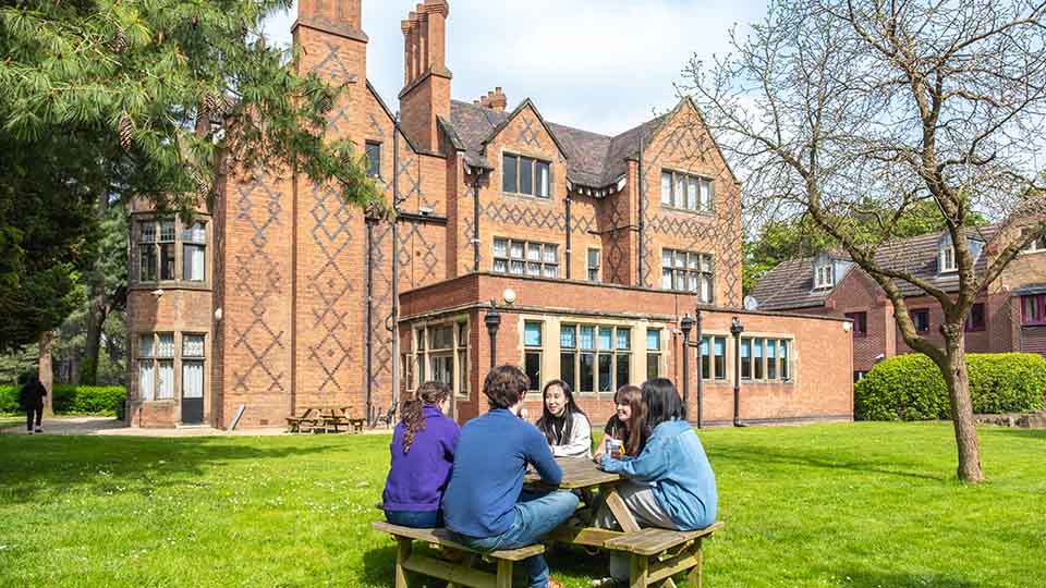 Fours students sitting outside postgraduate halls of residence on Loughborough campus