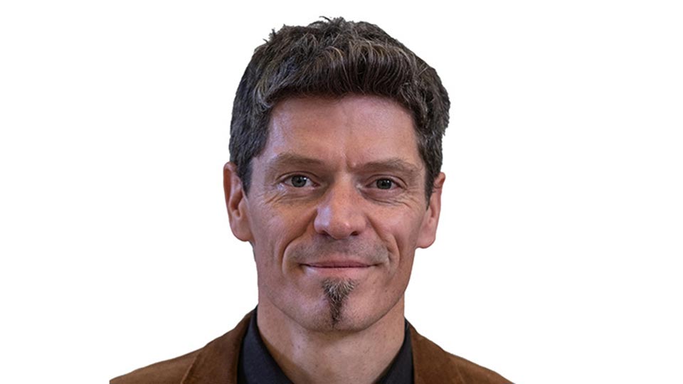 Chris smilng to camera in front of a white background