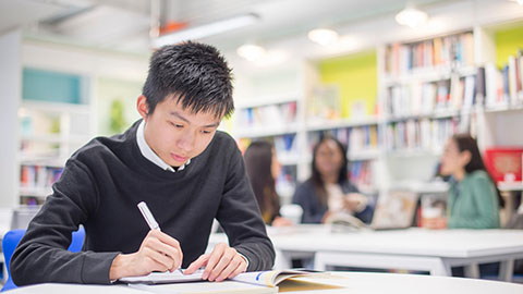 A student looking down and holding a pen at Loughborough University London