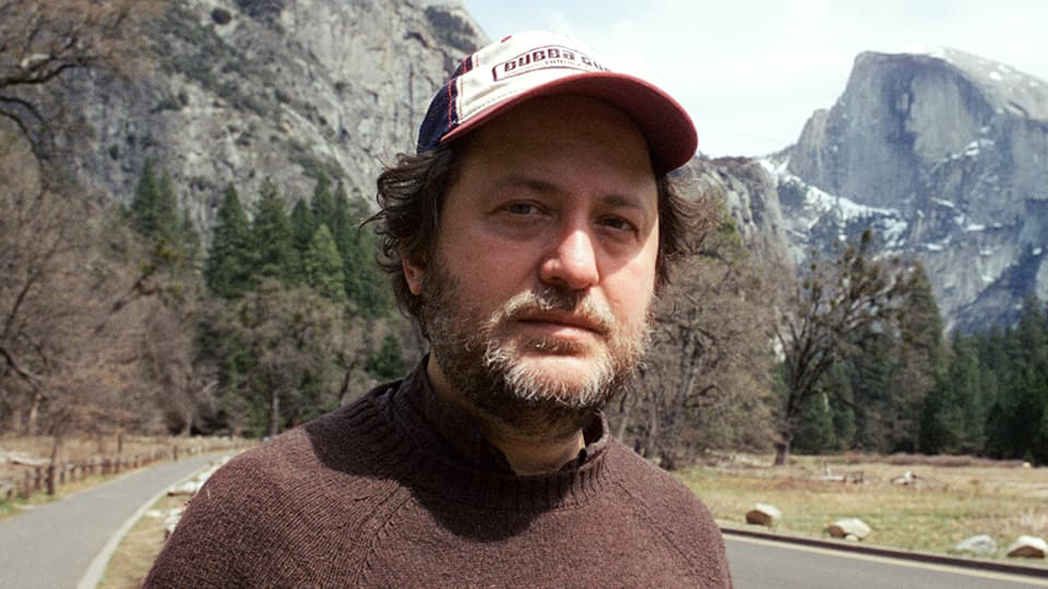 Avsar stood outside in front of mountains and trees