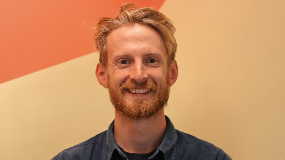 Brendan stood against a cream and orange background