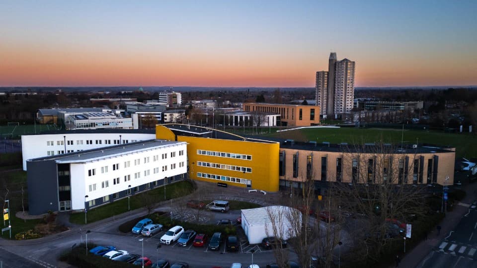 A drone shot of the business school building and car parking as it is getting dark
