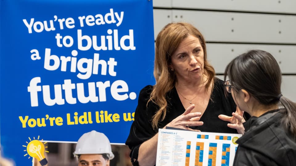 A student talking to a Lidl employee about careers