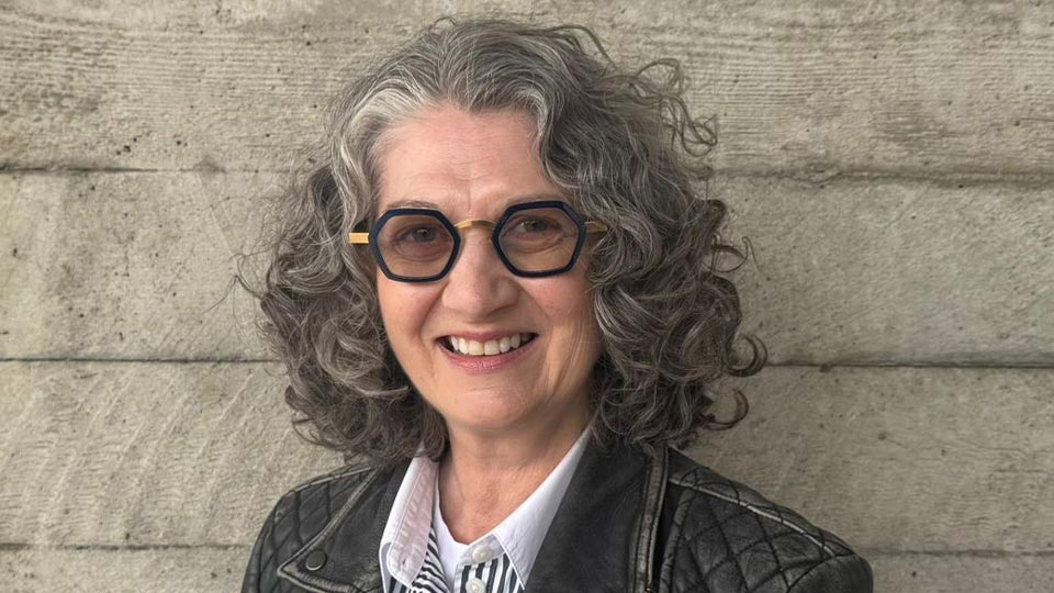 Carolyn stood in front of a wooden wall