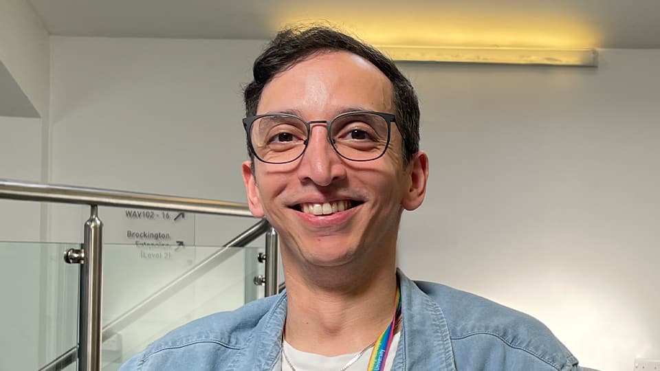Christopher sat near some stairs and against a grey background