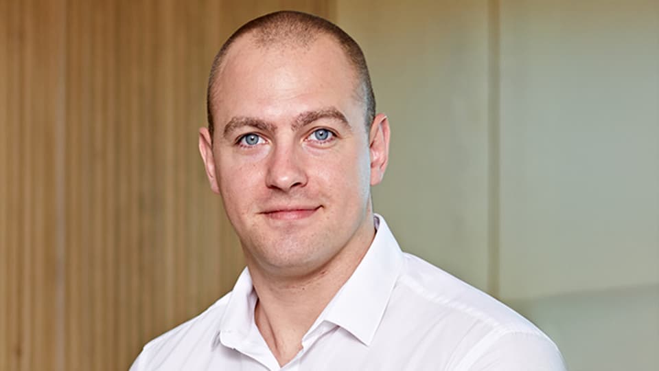 Dom stood in front of a textured and cream wall