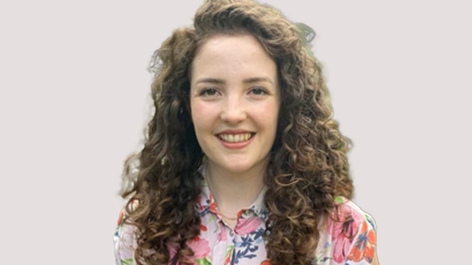 A female student with long curly hair smiling at the camera