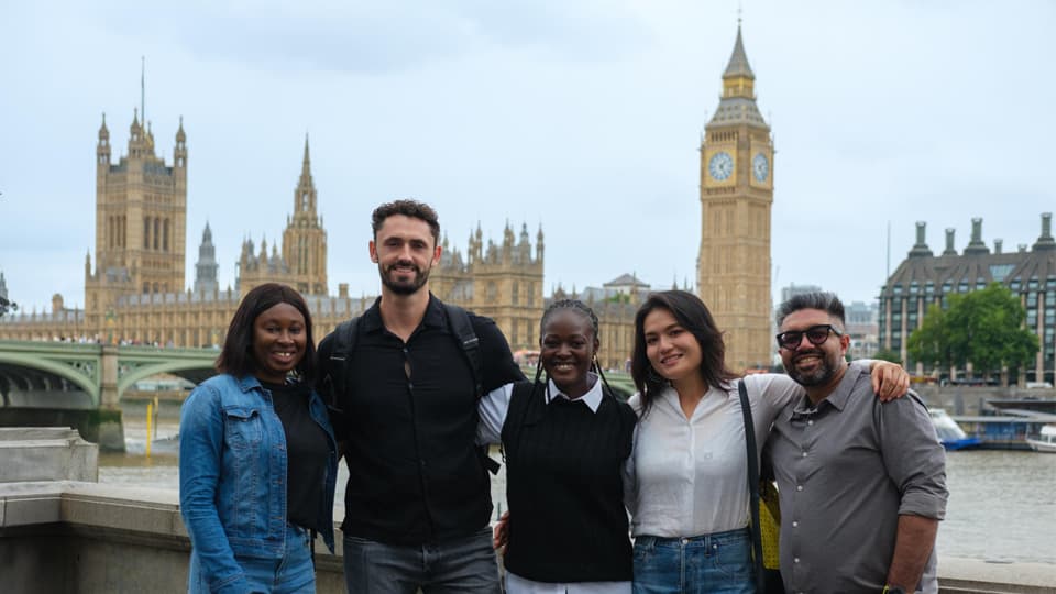 A group of postgraduate students standing in front of the houses of parliament