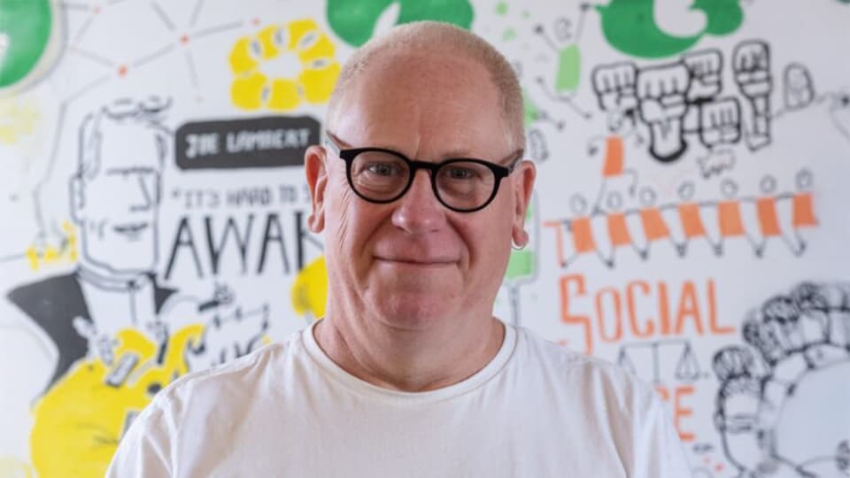 Michael stood in front of artistic wall with images and graphics