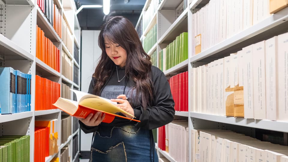 A female postgraduate student reading in the library