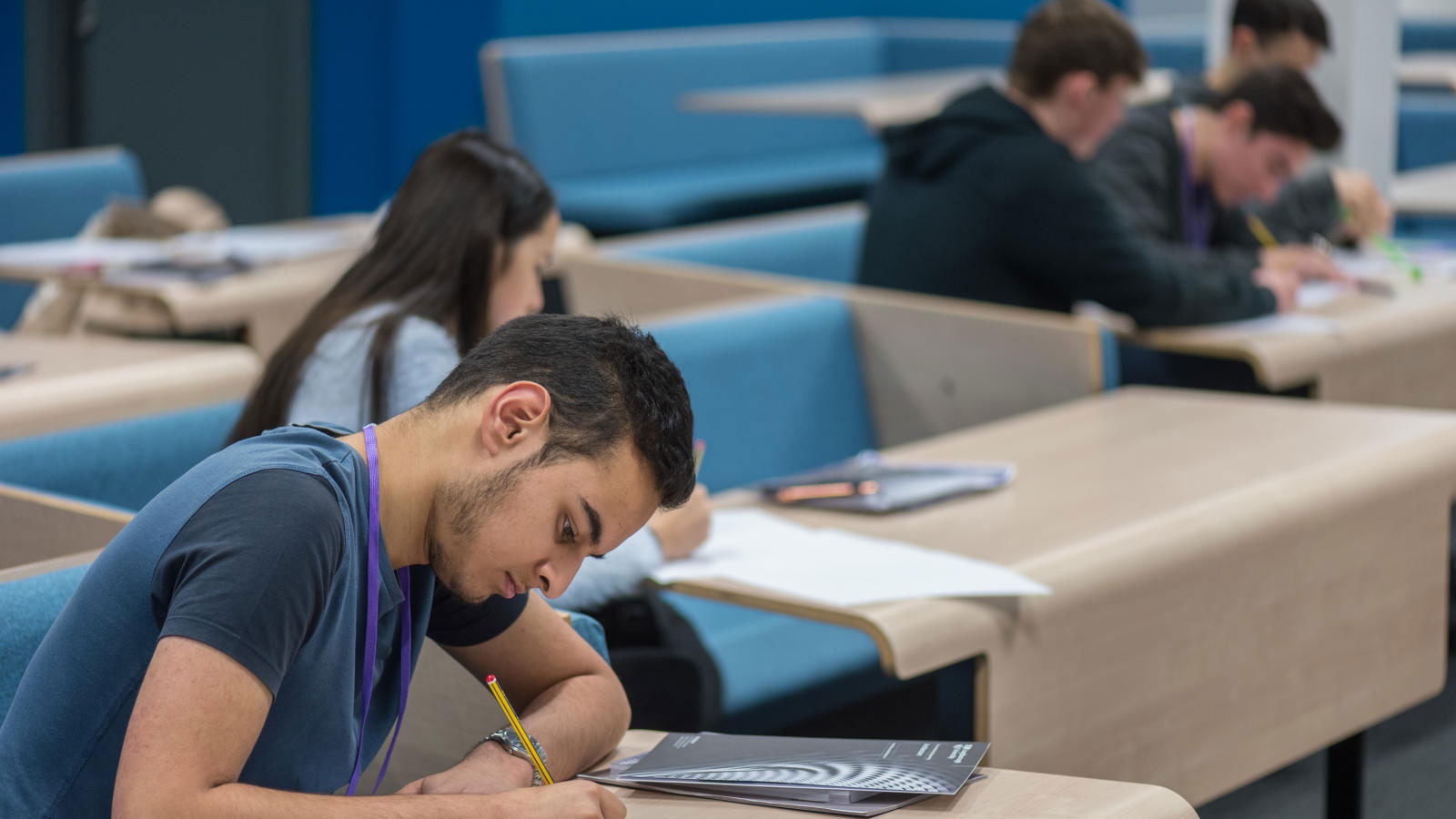 Students spaced out and sitting a desks writing.