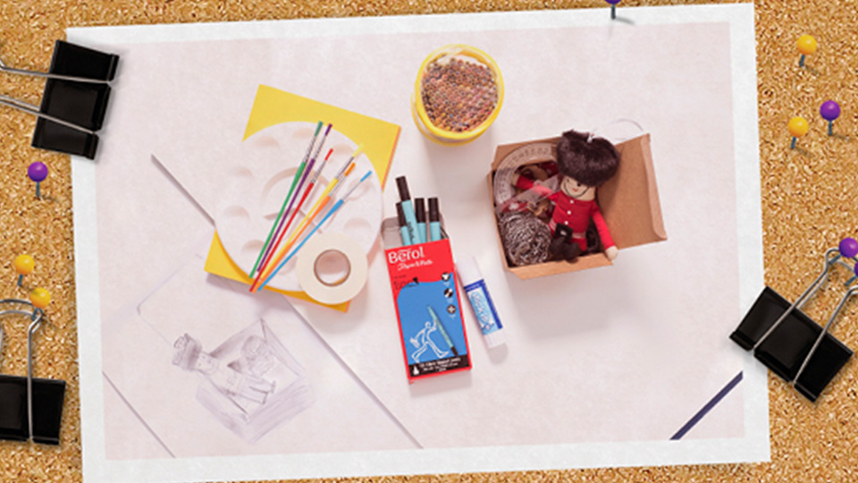 Art equipment including paintbrushes, pencils and pens with a cardboard box of random objects inside.
