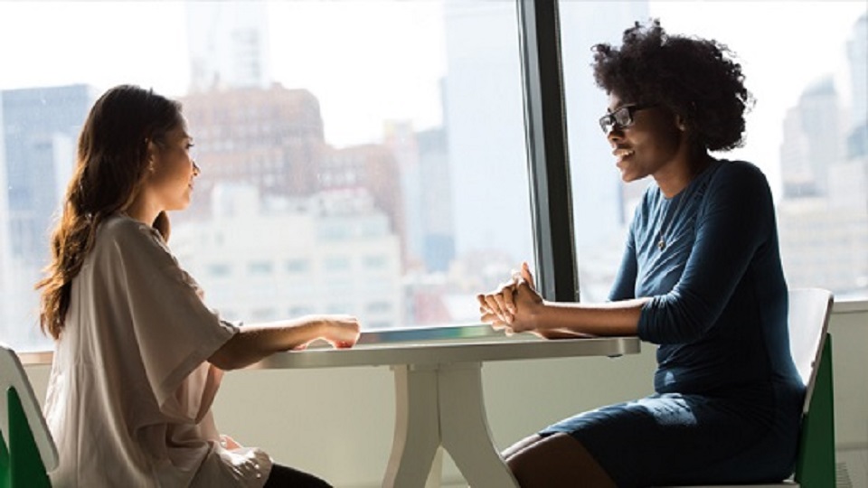 Two people sitting opposite each other at a round table.