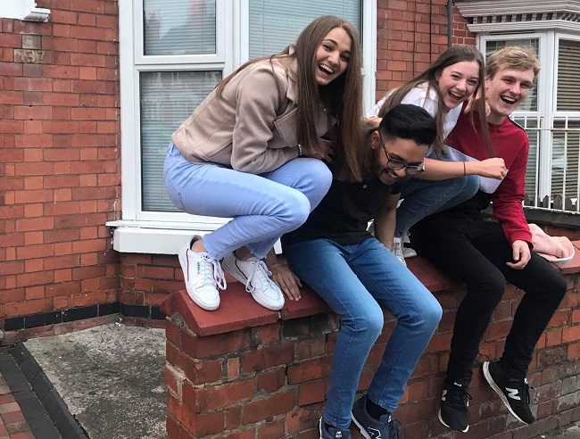 Eleanor and her three house mates sitting on a wall.