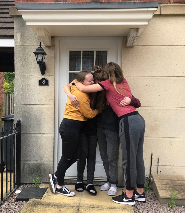 Caroline and three housemates hugging outside their house.