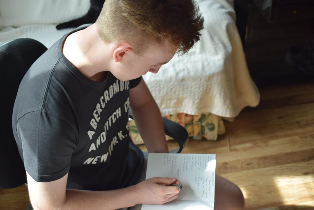 Lauren's brother taking notes in a notepad.