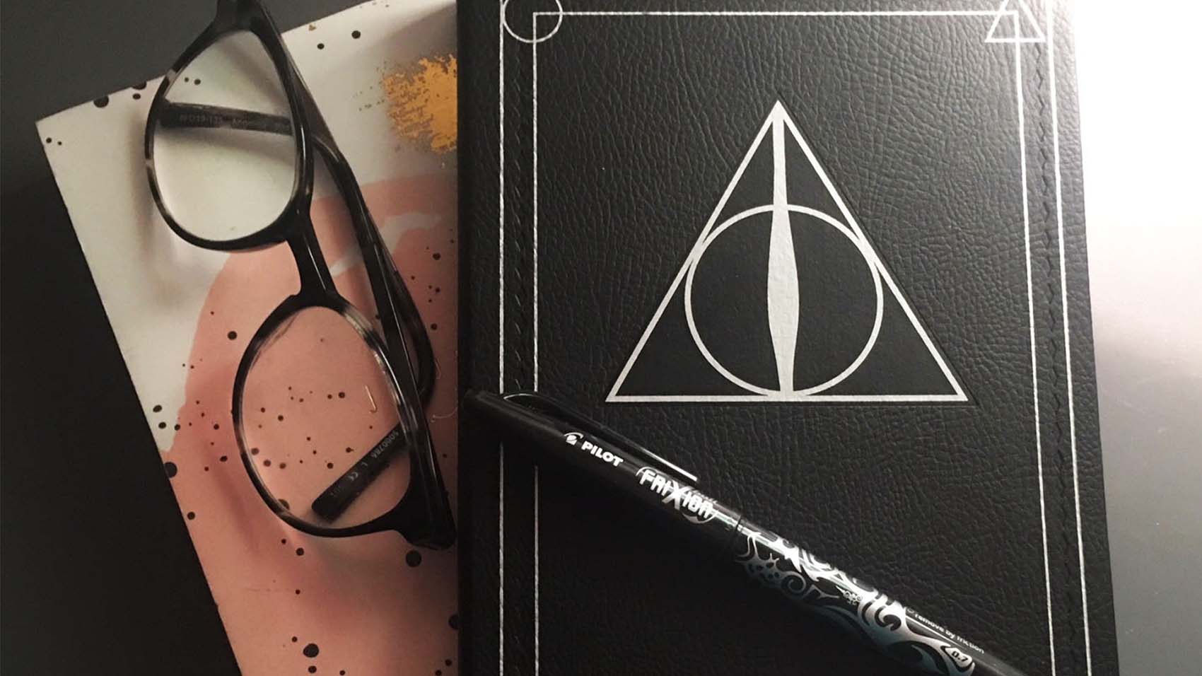 A black notebook, a black pen and black glasses.