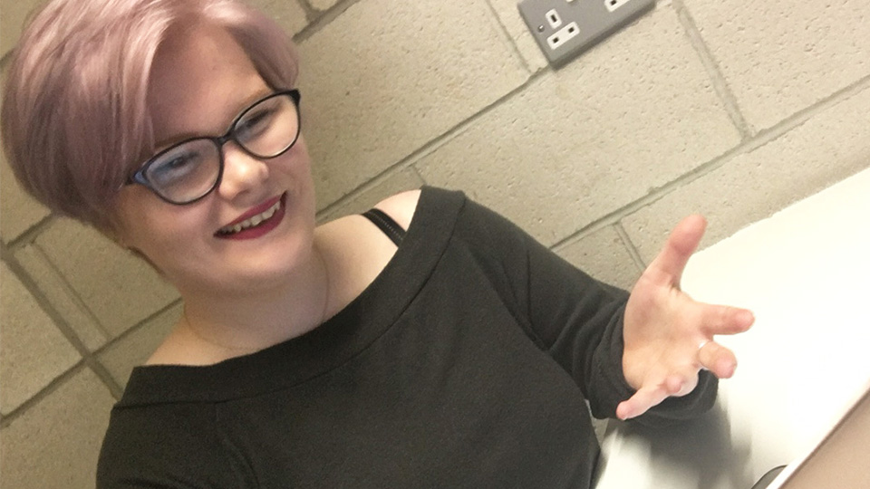 Miranda with her hand out in front of her explaining something to someone.