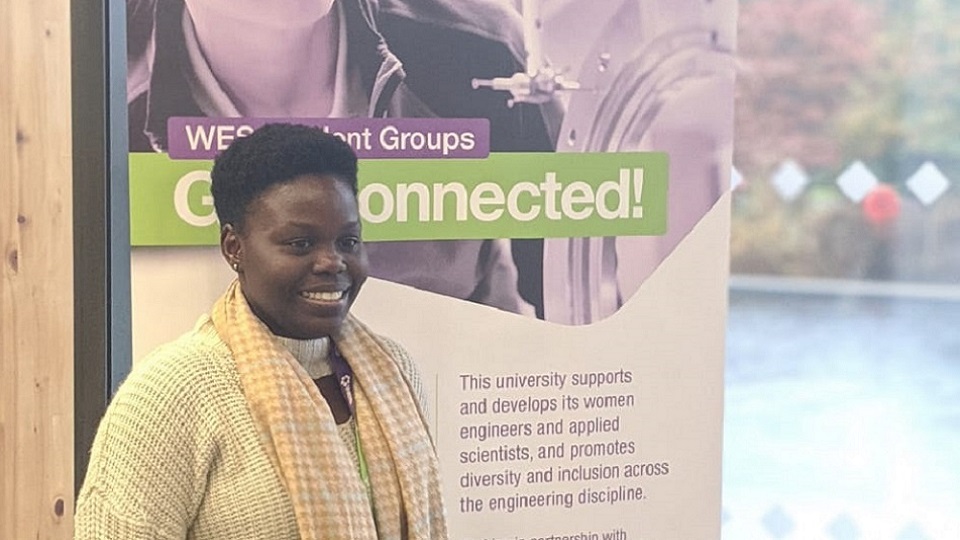 Seyi at the WES Student Conference in front of a WES banner. 
