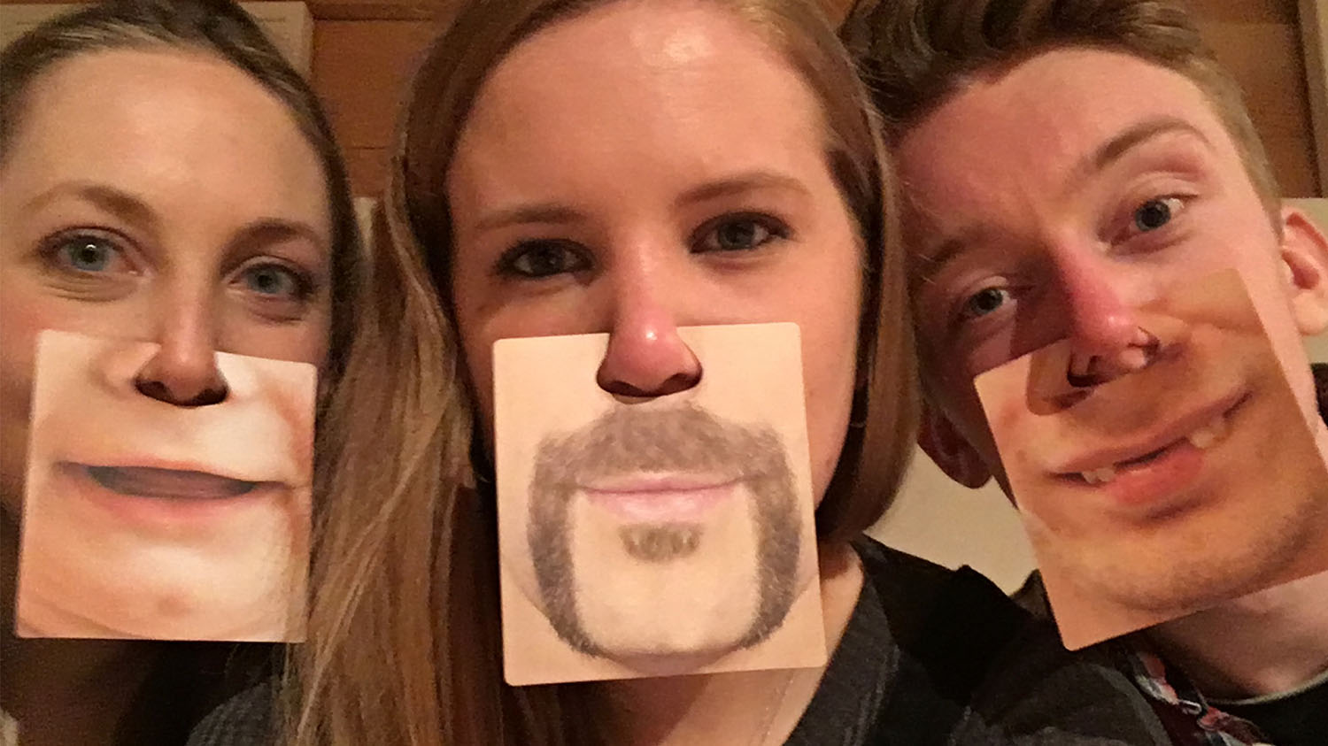 A selfie of Imogen and two friends with cards attached to their nose with other peoples chins on it, to make it look like they have a different chin.