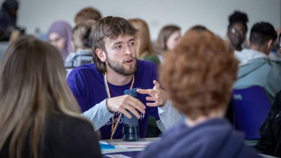 Student Ambassador talking to students around a table.