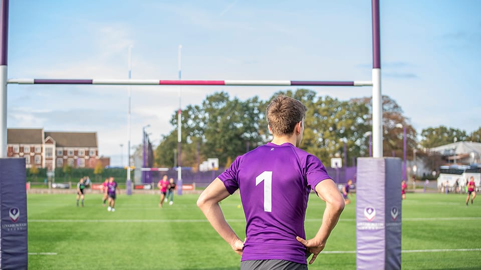A rugby player wearing purple kit with the number 1 on the back is facing the rugby pitch