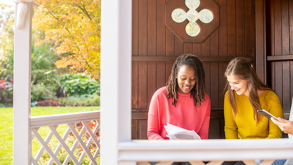 Two students sat outside looking at a document.