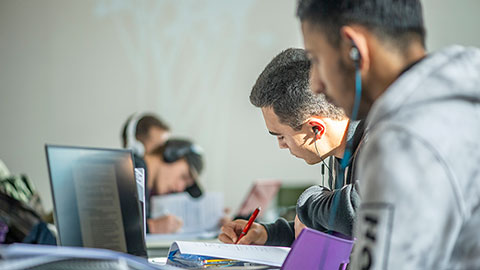 Two male students writing at a desk