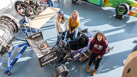 students standing next to the Formula Student racing car