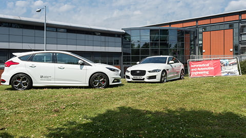 two cars outside a building on campus